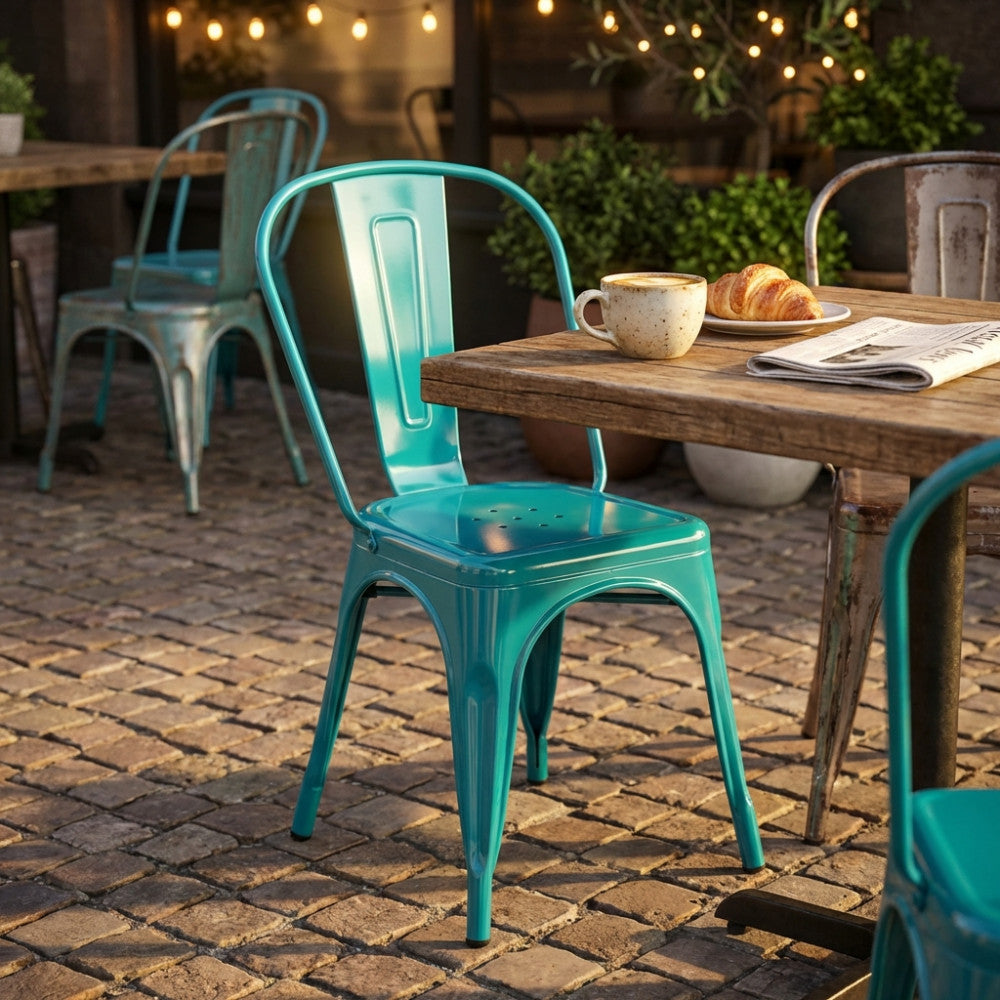 Sedia in metallo verde petrolio stile industrial ambientata all'aperto accanto a un tavolo in legno con colazione.