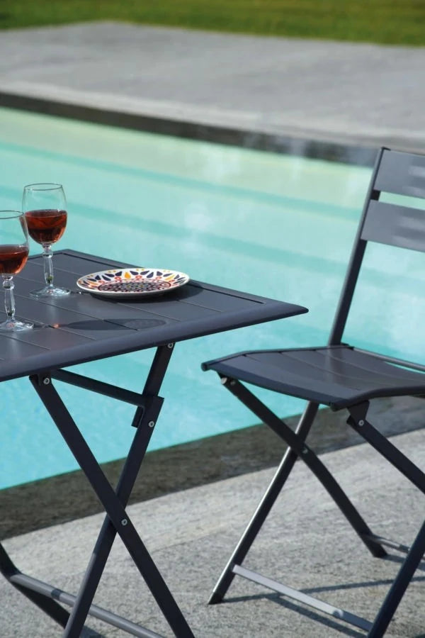 Sedia Lucca Pieghevole in Alluminio Antracite con design a listelli, resistente e salvaspazio per esterni, ambientata tavolino