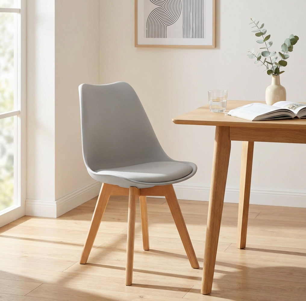 Sedia Marsiglia grigia in plastica e legno posizionata accanto a un tavolo da pranzo in rovere illuminato dalla luce naturale.