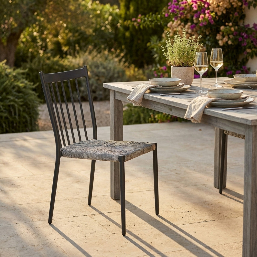 Vista laterale della sedia Martinica impilabile, che mostra l'intreccio tattile del wicker e la struttura robusta in alluminio grigio.