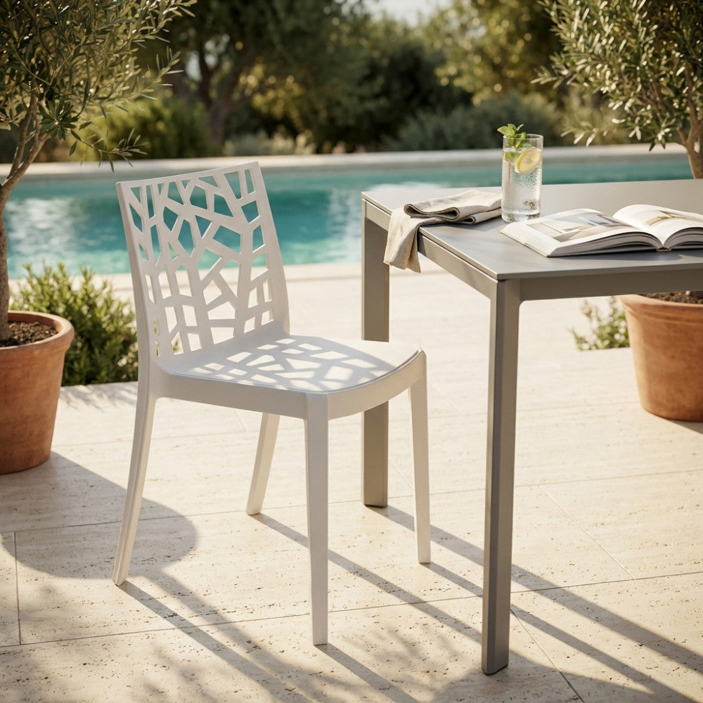 Sedia Matrix con schienale geometrico traforato abbinata a un tavolo grigio a bordo piscina.