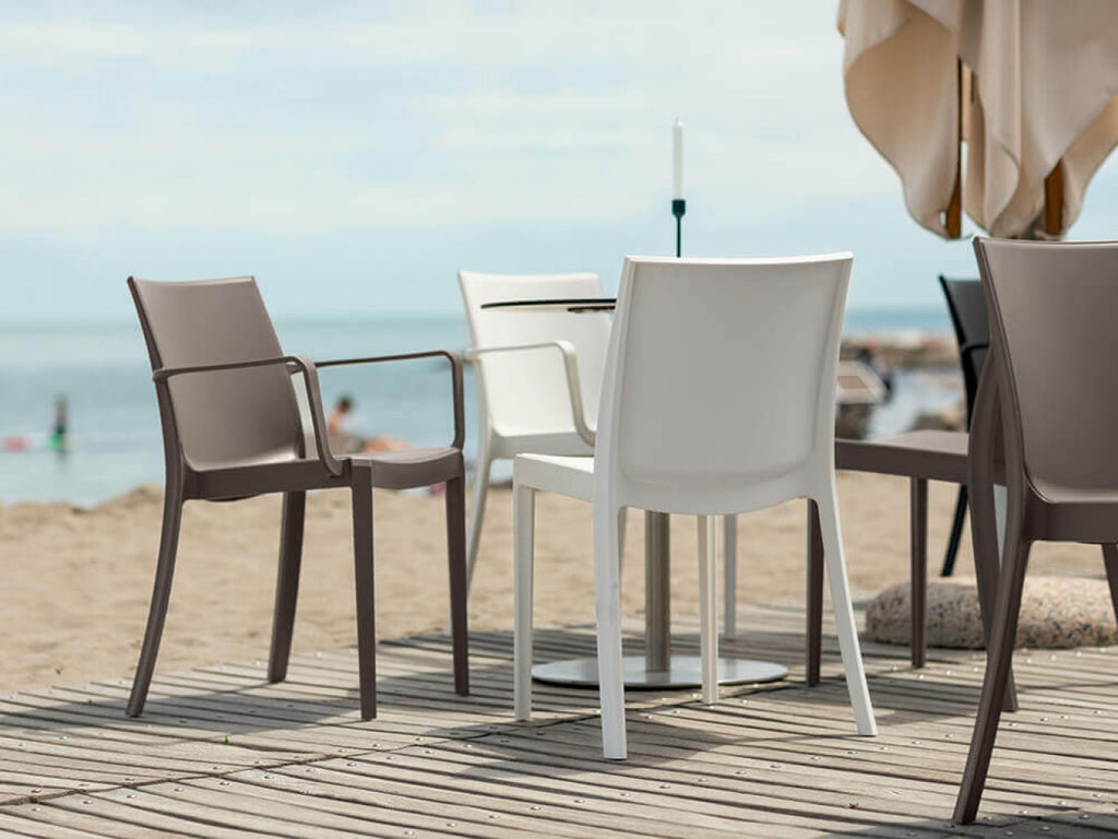 Sedie di design in polipropilene bianco e tortora collocate in un elegante dehor sulla spiaggia.