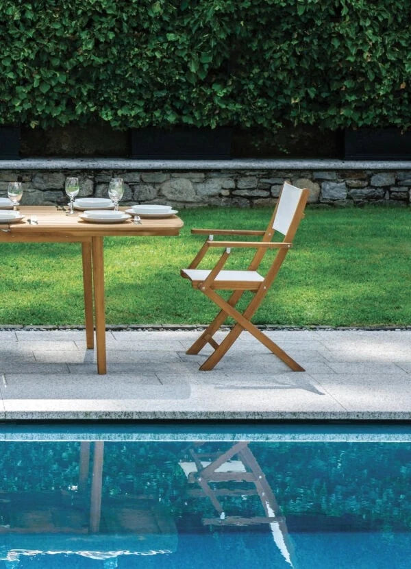 Sedia pieghevole Venturina con braccioli, in Legno di Acacia e seduta in Textilene ecrù per esterni, ambientata a bordo piscina