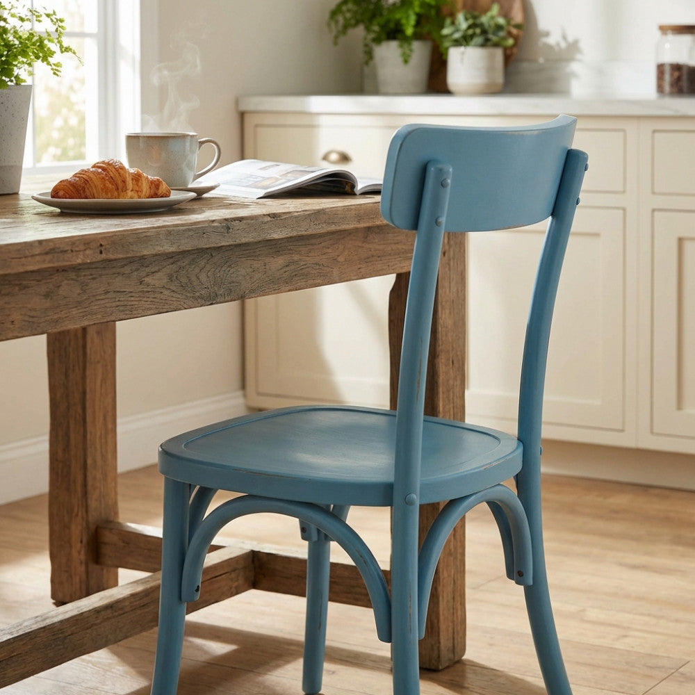 Sedia Polly azzurra in stile shabby chic posizionata accanto a un tavolo da pranzo in legno rustico con colazione.