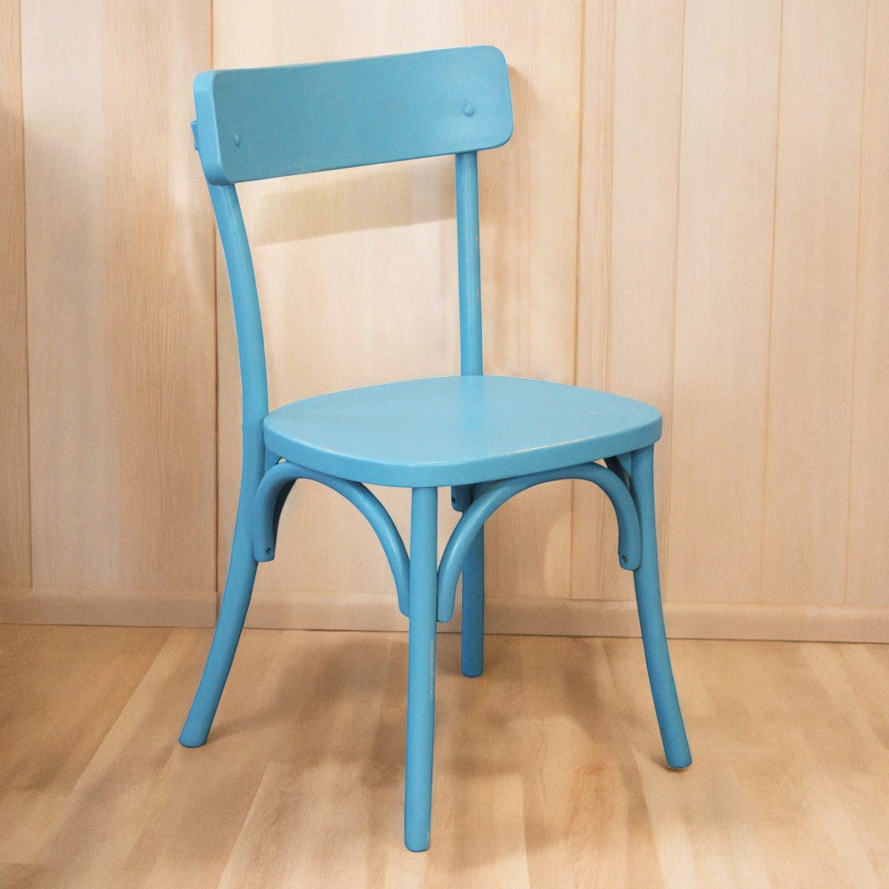 Sedia Polly azzurra fotografata in studio contro una parete con pannelli in legno chiaro.