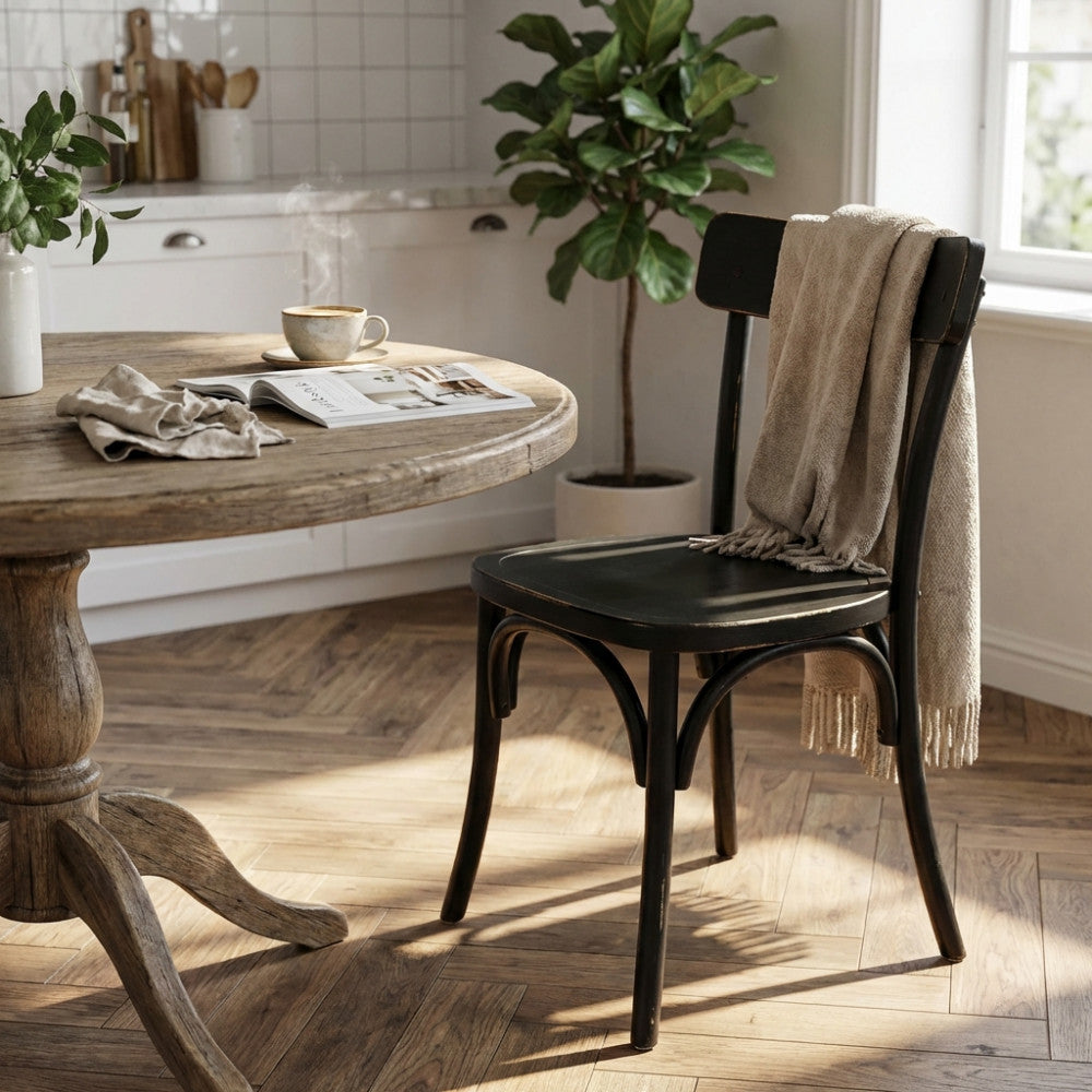 Sedia Polly nera in stile shabby chic posizionata accanto a un tavolo in legno rustico in una sala da pranzo luminosa.