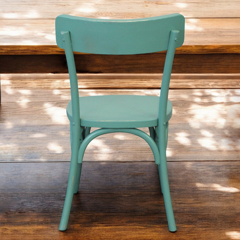 Vista posteriore della sedia Polly verde inserita in un contesto rustico con pavimento in legno.