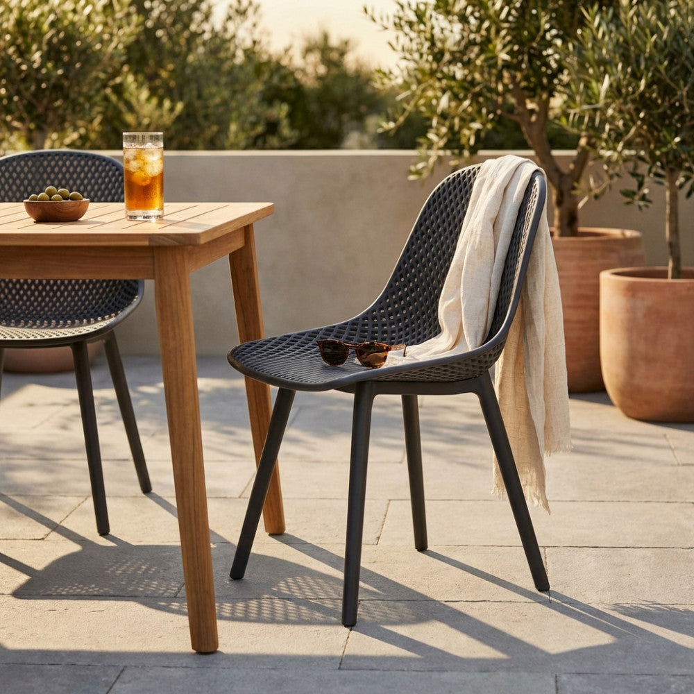Sedia Vichy color taupe con un telo in lino appoggiato sullo schienale, situata su un patio in pietra vicino a un tavolo in legno.