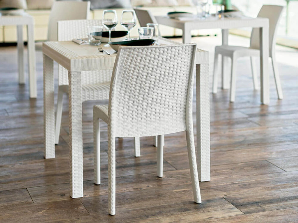 Sedia da giardino Virginia Bianca in plastica stampata effetto Wicker, design elegante resistente agli UV, ambientata in un ristorante con tavolo rettangolare