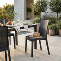 Sedia Virginia in wicker tortora ambientata a bordo piscina con tavolo da pranzo scuro e decorazioni naturali.