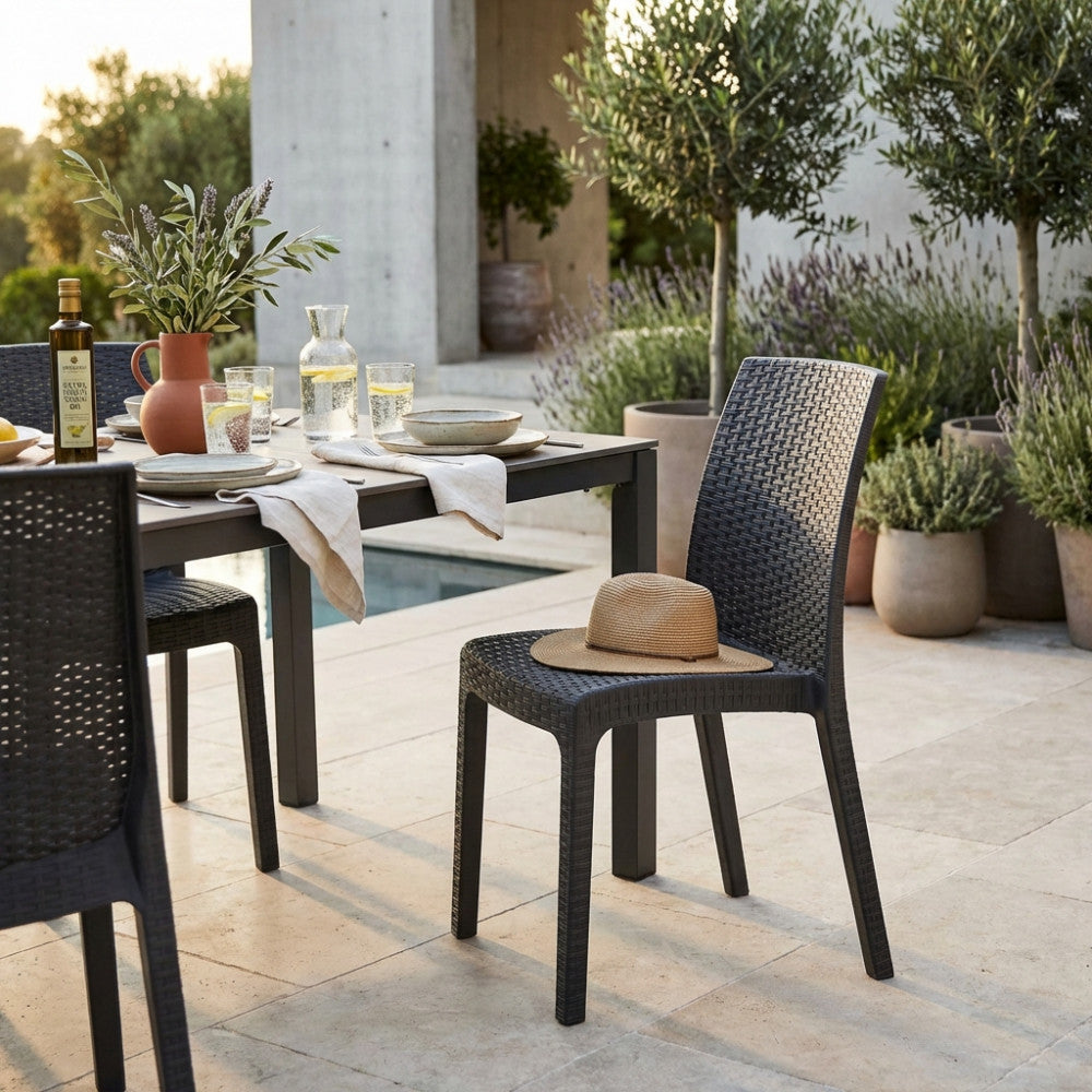 Sedia Virginia in wicker tortora ambientata a bordo piscina con tavolo da pranzo scuro e decorazioni naturali.