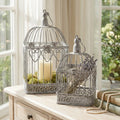 Set di due gabbie decorative in acciaio bianco ossidato, allestite con candele e lavanda su un mobile in legno chiaro.