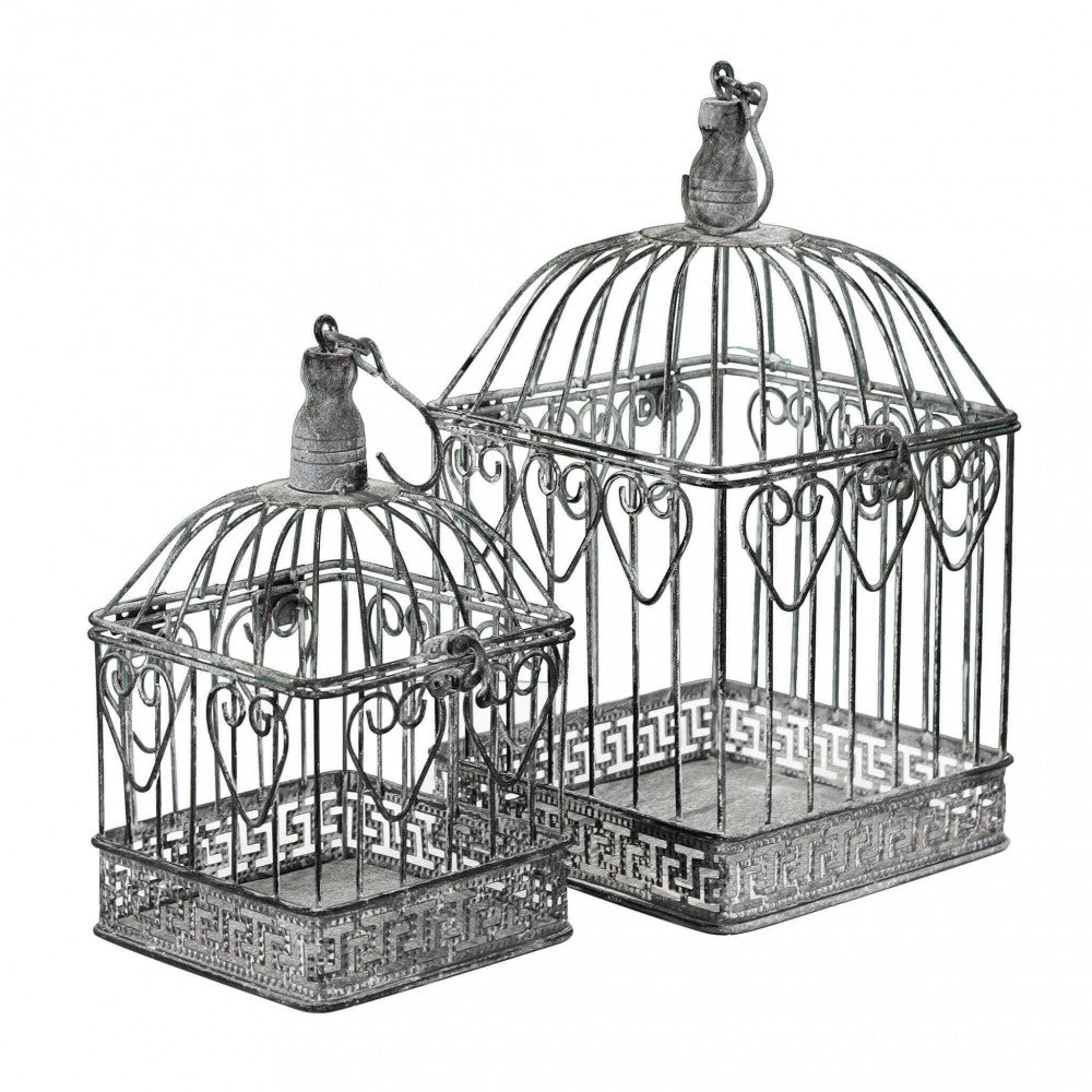 Prospettiva angolata delle due gabbie decorative in bianco ossidato, mostrando la struttura a cupola e i dettagli di chiusura.