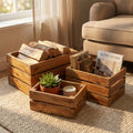 Set di 3 cassette contenitore in legno di mogano disposte su un tappeto chiaro, utilizzate per riporre legna, libri e candele in un salotto.
