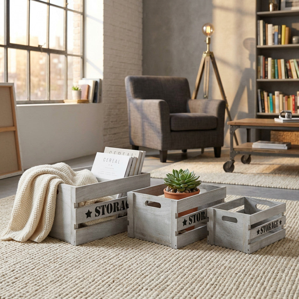 Set di 3 cassette in legno grigio Séline disposte su un tappeto chiaro, contenenti riviste, un plaid e una pianta.