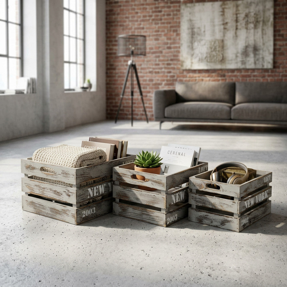 Set di 3 cassette Théa in legno grigio stile industrial, disposte sul pavimento di un loft luminoso con divano moderno sullo sfondo.