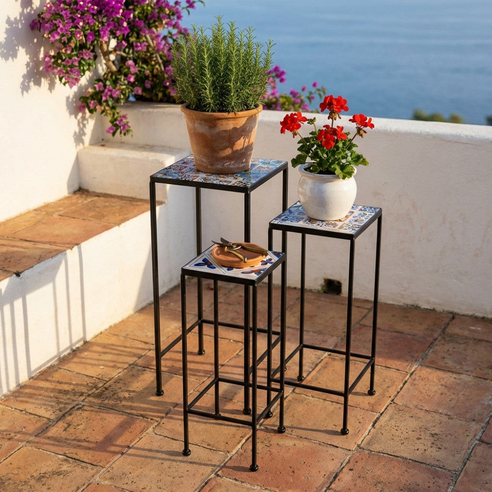 Set di tre fioriere in ceramica con decori bianco oro, disposte a gradinata su un terrazzo soleggiato con vista mare e piante aromatiche.