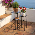 Set di tre fioriere in ceramica con decori bianco oro, disposte a gradinata su un terrazzo soleggiato con vista mare e piante aromatiche.