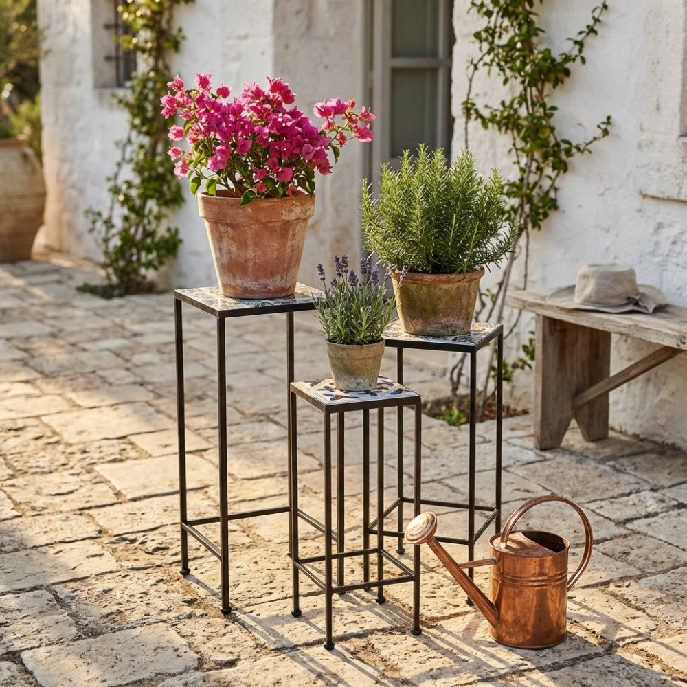Composizione di tre fioriere vintage in ceramica e metallo su un patio in pietra, arricchite da vasi in terracotta con lavanda e rosmarino.