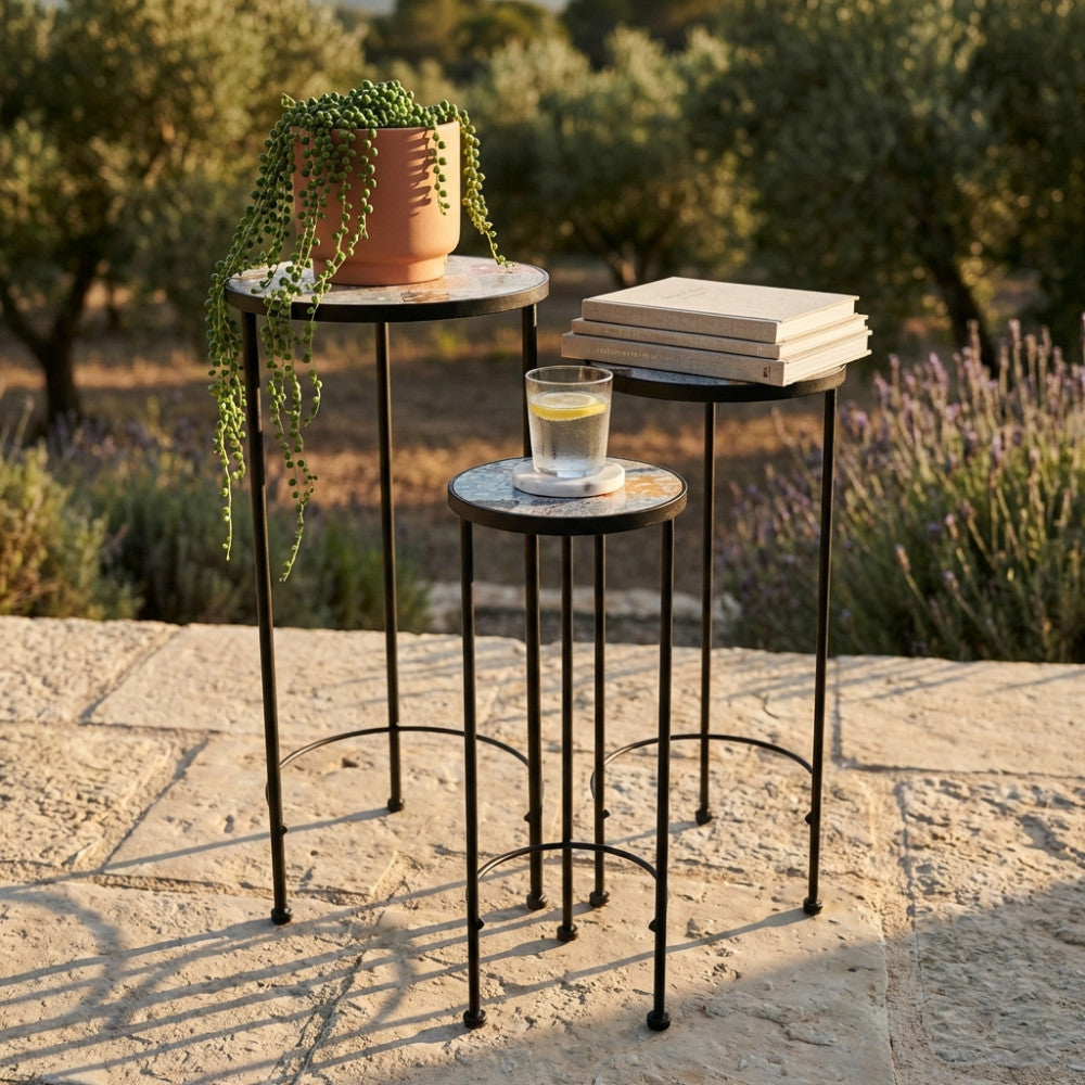 Dettaglio delle tre fioriere vintage con piano a mosaico, allestite all'aperto con libri, un bicchiere d'acqua e una pianta ricadente su sfondo naturale.