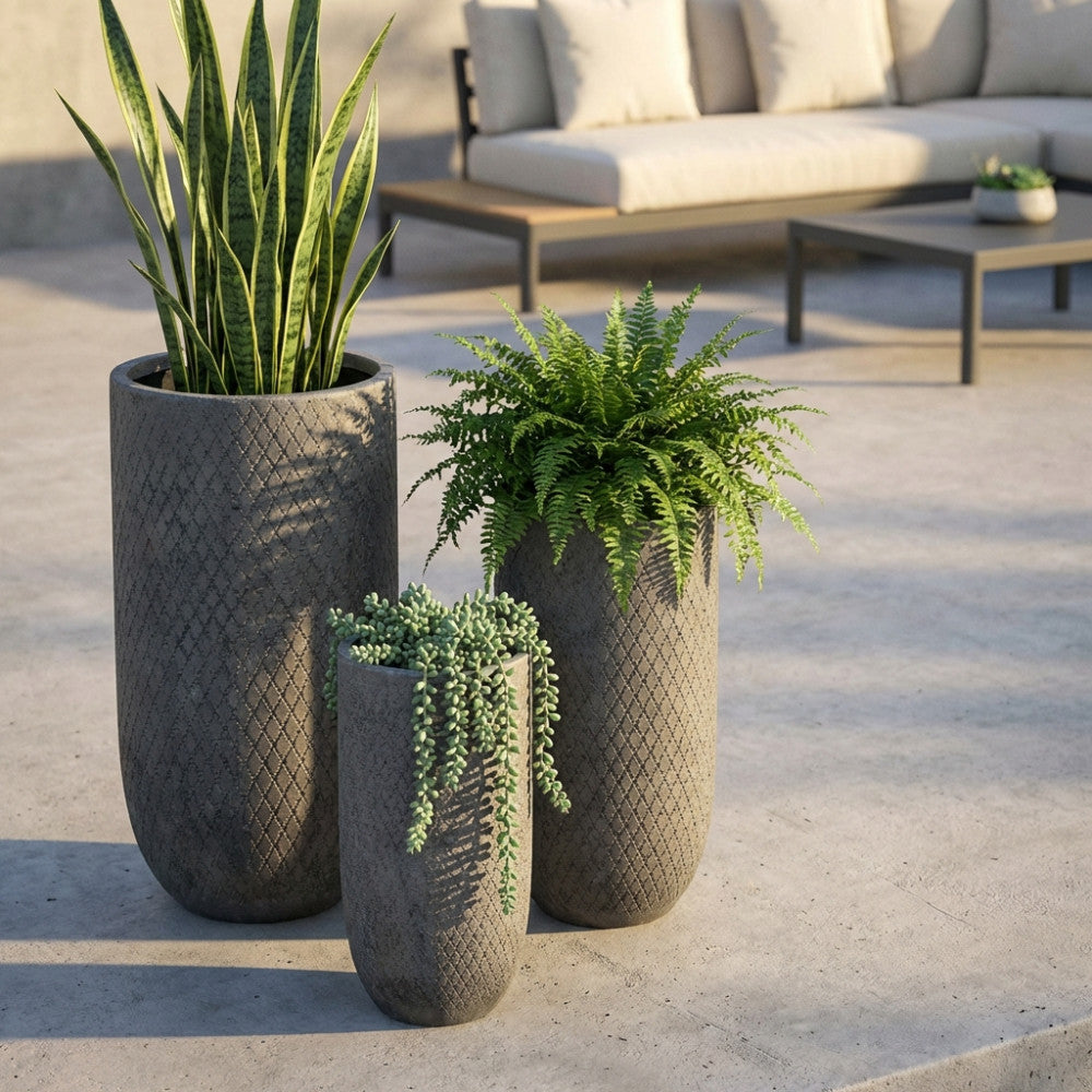 Set di 3 vasi Tiglio in fibra di argilla grigia ambientati su una terrazza moderna con piante ornamentali.