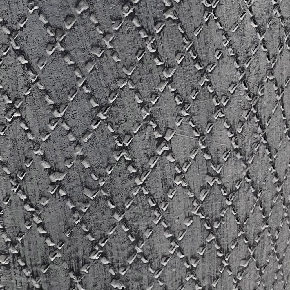 Dettaglio ravvicinato della texture a rilievo con motivo a rombi sulla superficie in fibra di argilla grigia.