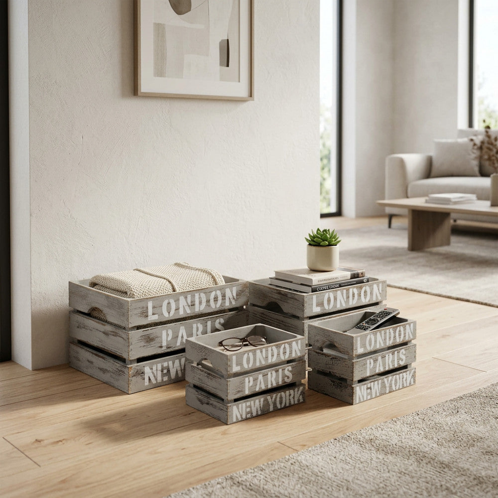 Set di 4 cassette in legno grigio Nicole disposte a terra in un soggiorno luminoso, utilizzate per riporre coperte e telecomandi.