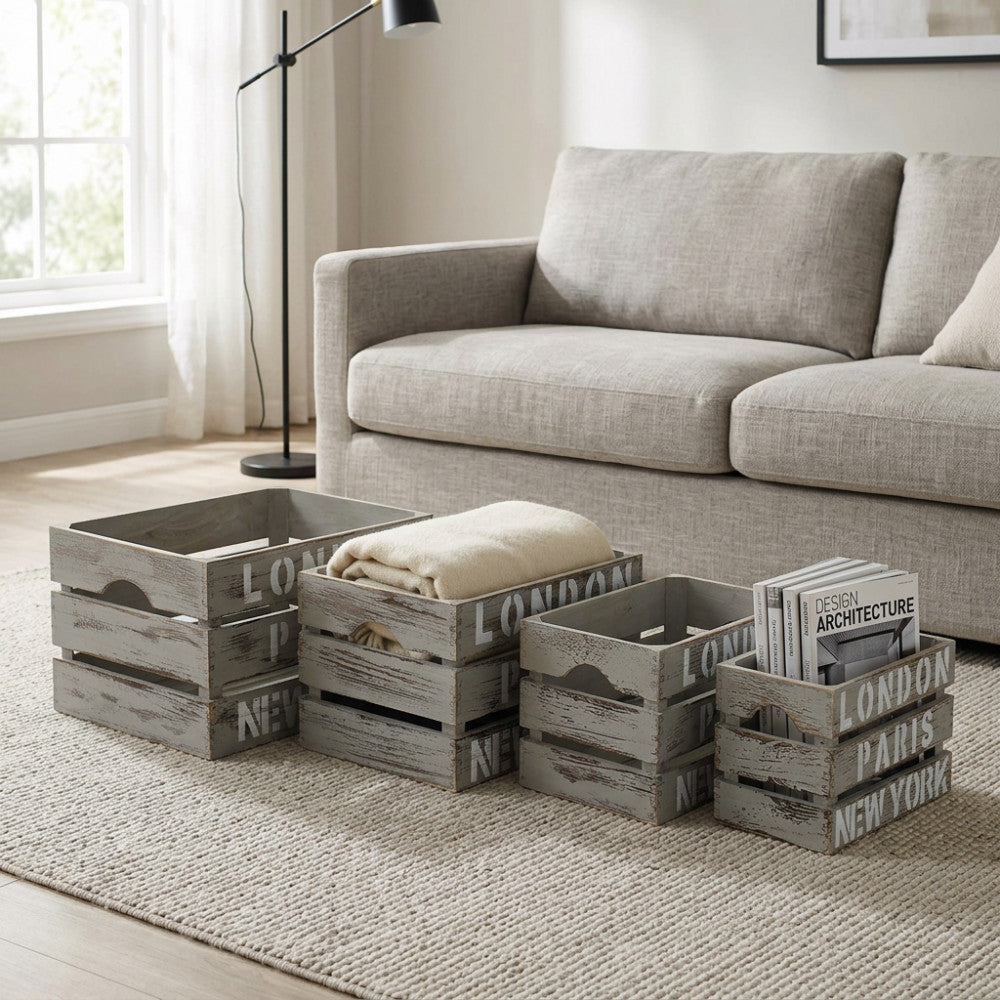 Tre cassette contenitore in legno stile industriale allineate davanti a un divano grigio, contenenti plaid e riviste di architettura.