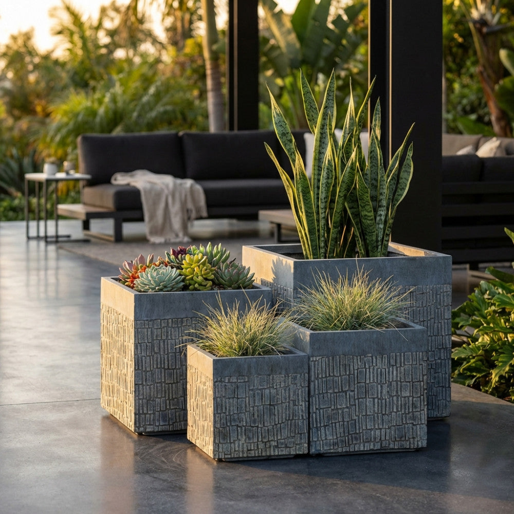 Vasi architettonici Geraneo posizionati su un patio moderno, arricchiti da sansevierie e succulente con un divano lounge sullo sfondo.
