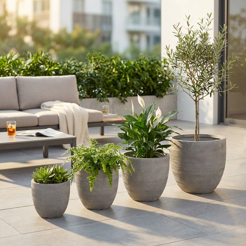 Vasi Primula grigi di diverse dimensioni allineati su una terrazza moderna, affiancati da un divano lounge elegante.