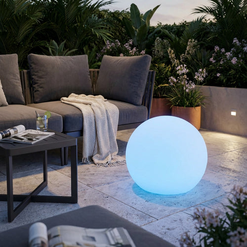 Sfera luminosa Gemini con luce azzurra in un elegante patio esterno vicino a un divano moderno.