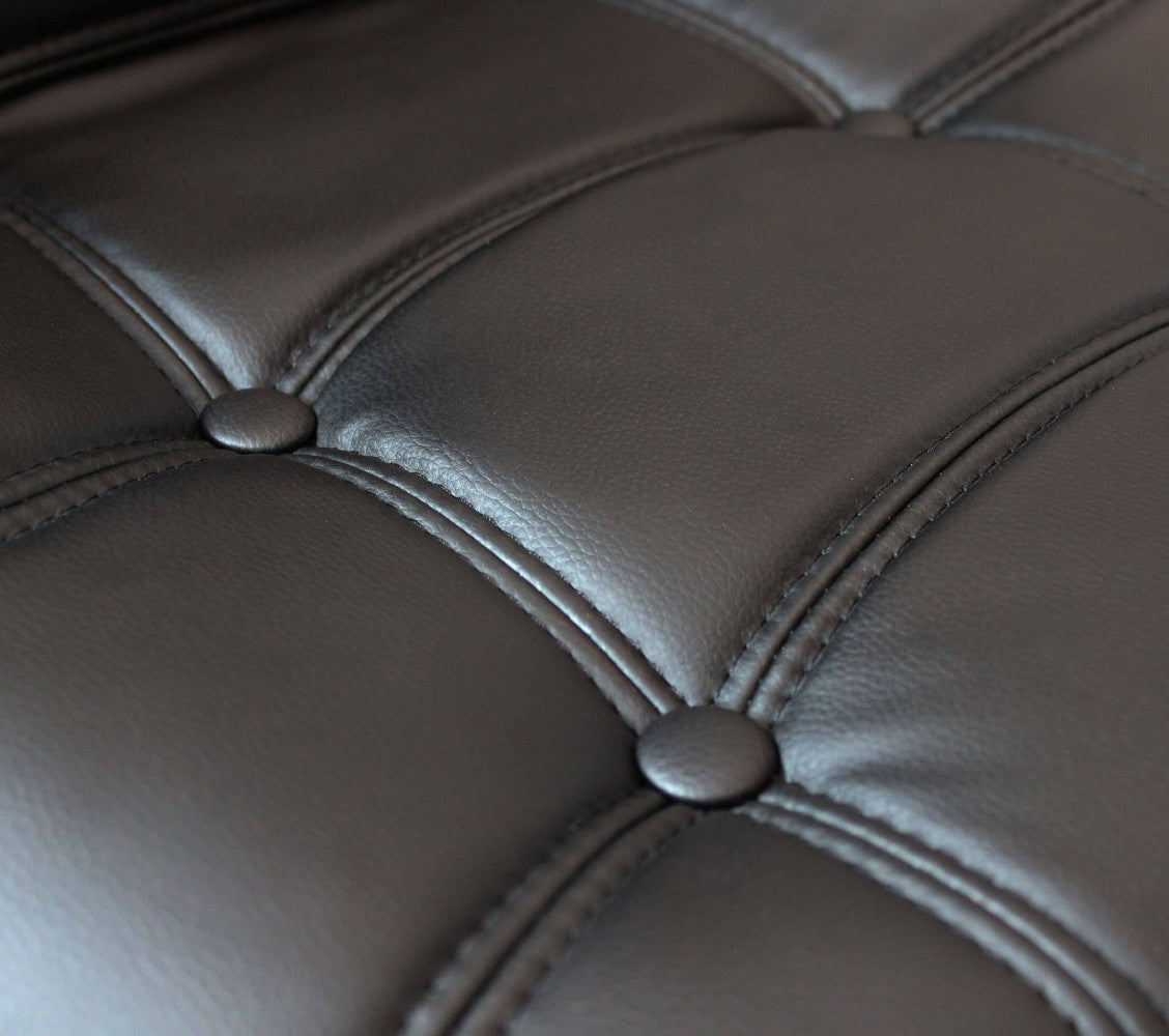 Primo piano della texture in ecopelle nera con impunture e bottoni decorativi dello sgabello FLYNN.