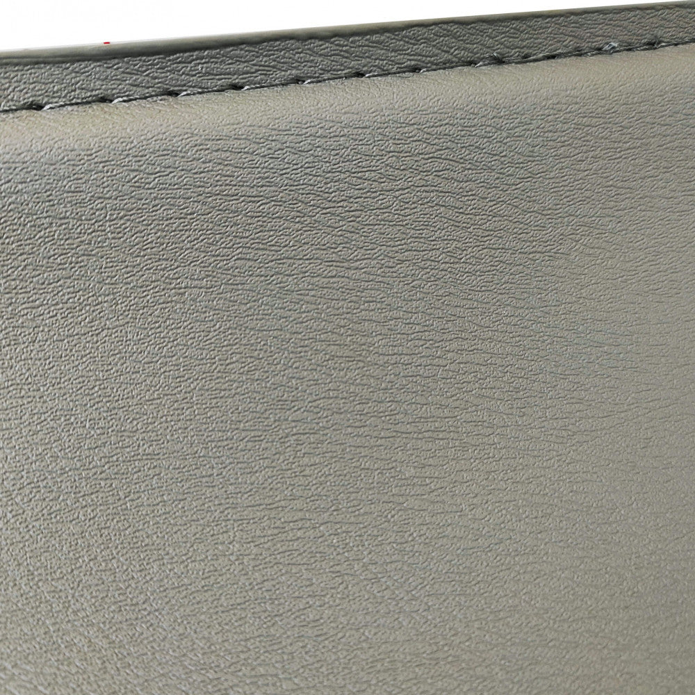 Macro fotografia della texture in ecopelle grigio chiaro dello sgabello Jake, evidenziando le cuciture sartoriali di precisione.