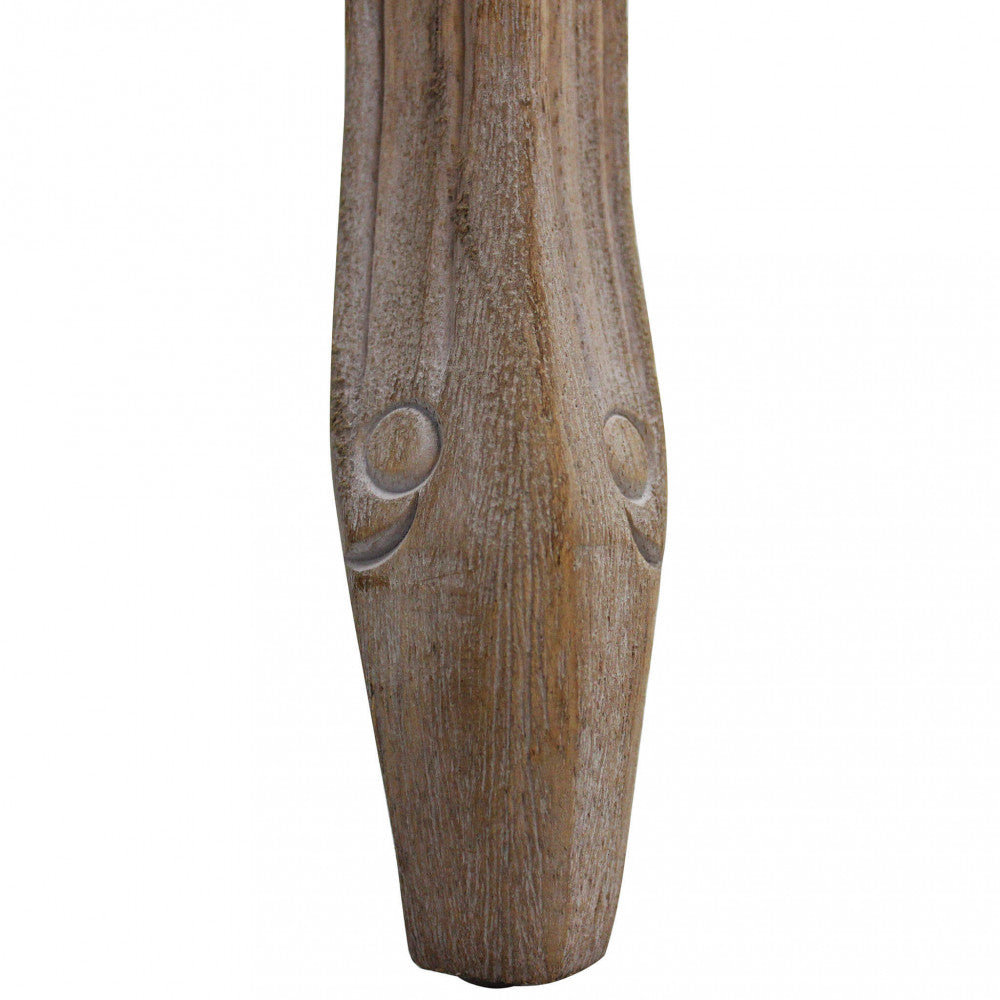 Dettaglio del piedino in legno intagliato dello sgabello Marly, che mostra la finitura anticata e la solidità del materiale.
