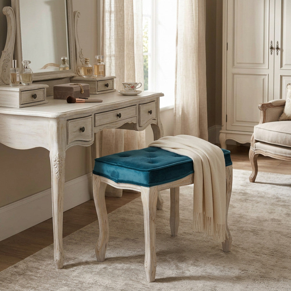 Sgabello classico in velluto blu abbinato a una toeletta in legno decapato.