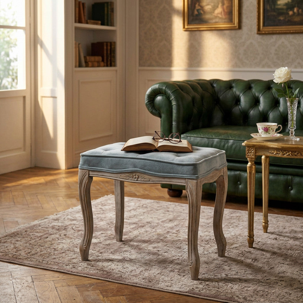 Sgabello Marly in velluto grigio ambientato in un salotto classico con divano Chesterfield verde.