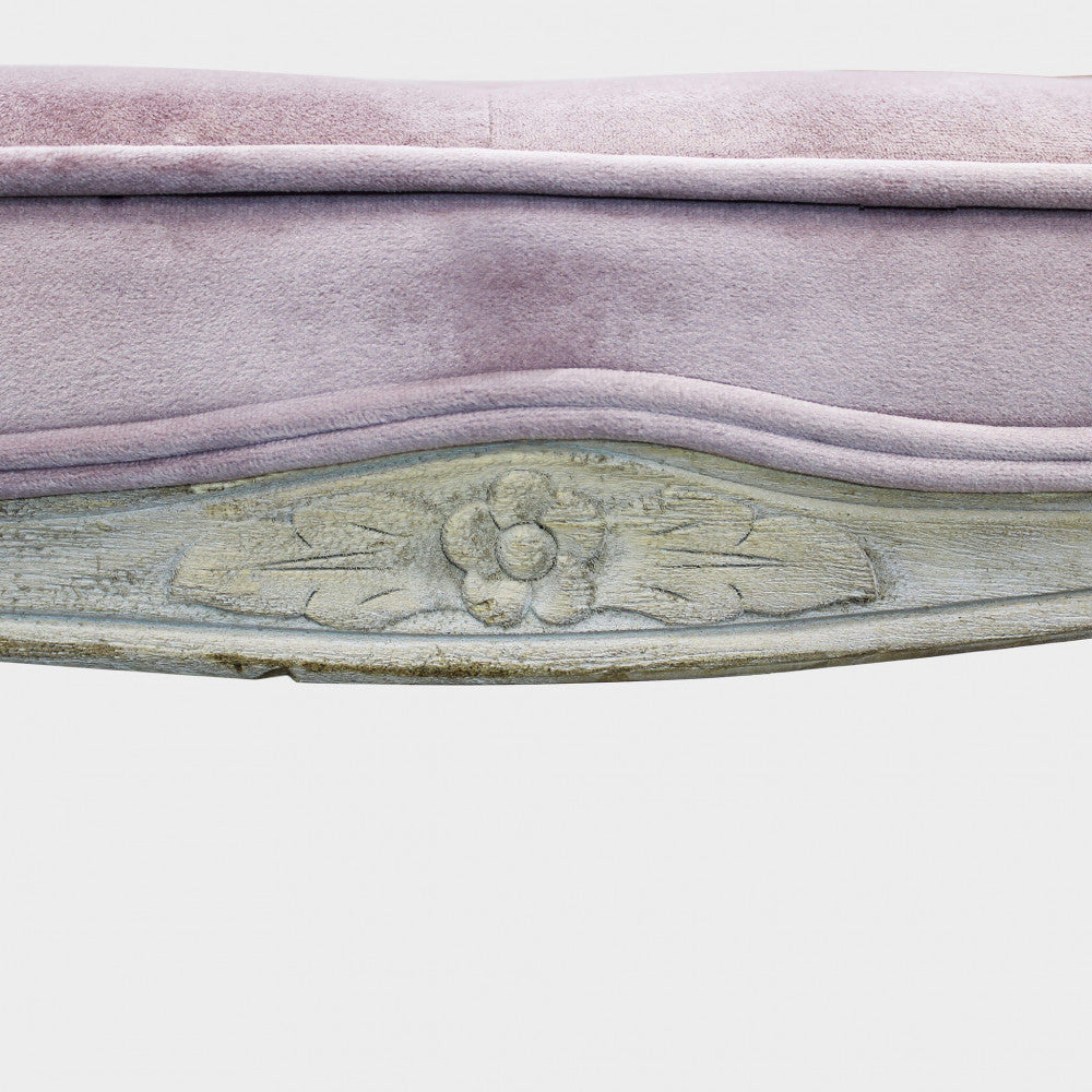 Primo piano della seduta in velluto rosa e del dettaglio floreale intagliato a mano sulla struttura in legno dello sgabello Marly.