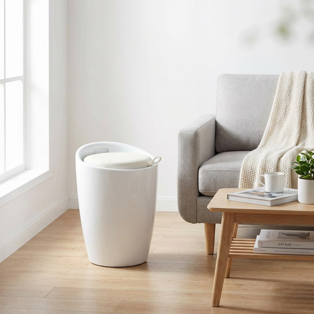 Pouf sgabello Cliff in plastica bianca ambientato in un luminoso soggiorno moderno accanto a un divano grigio.