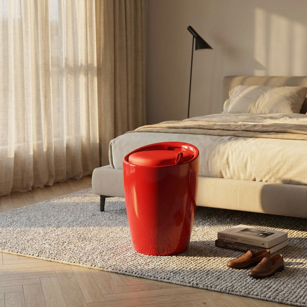 Sgabello pouf rosso di design posizionato accanto a un letto moderno su un tappeto materico in una camera da letto.