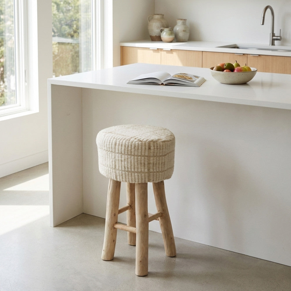 Sgabello nordico Valentin con seduta in cotone e lana di fronte a un bancone cucina bianco.