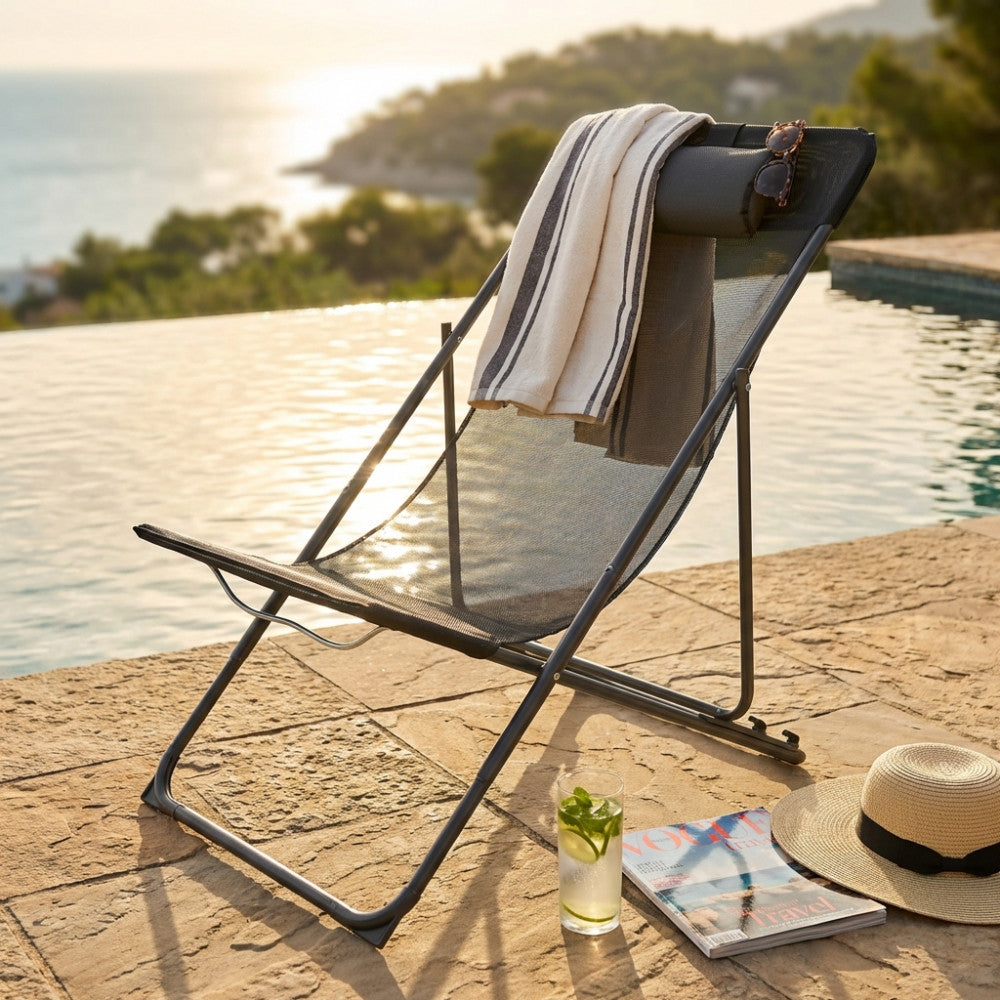 Sedia a sdraio pieghevole Mambo in metallo nero e textilene a bordo piscina, decorata con telo mare a righe e occhiali da sole