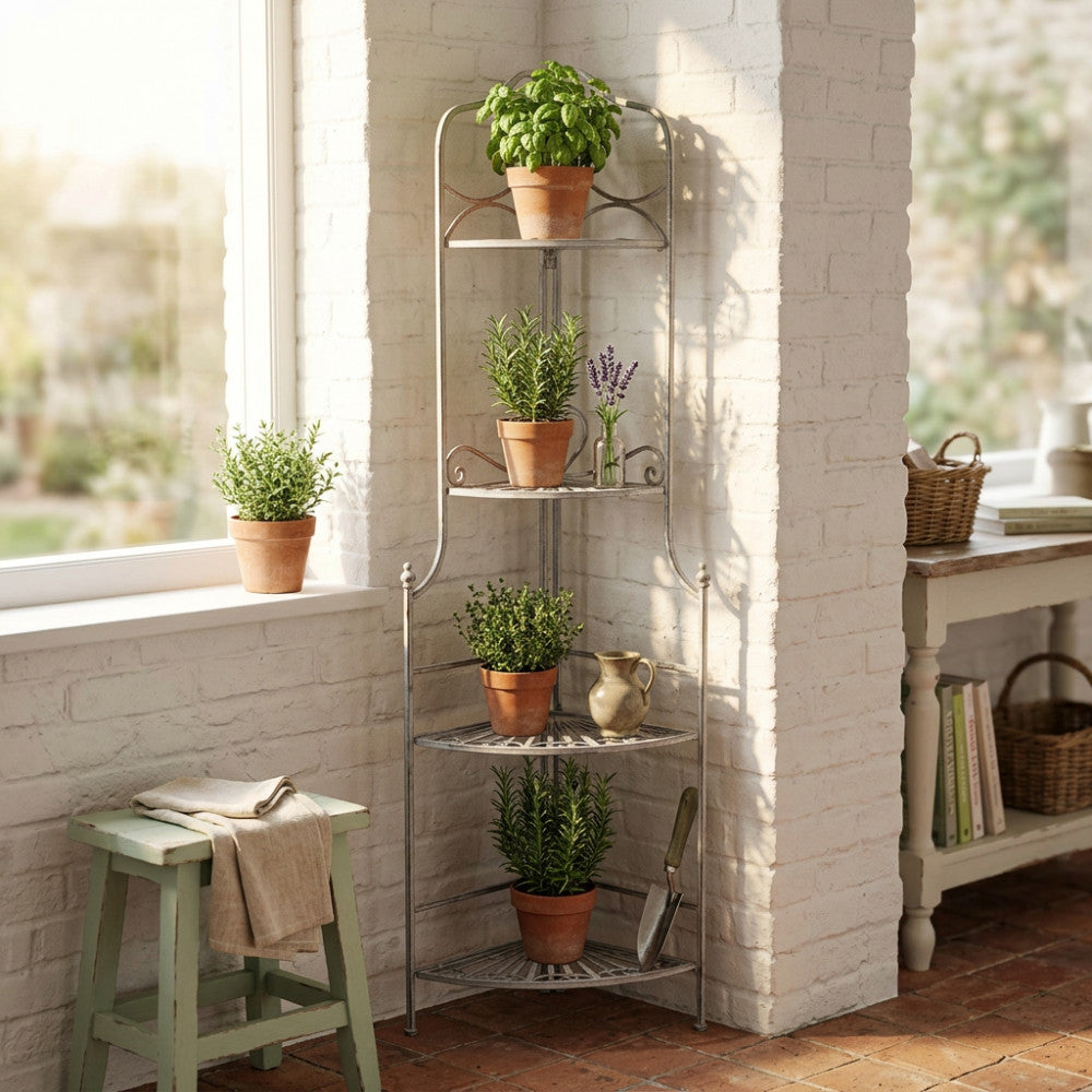 Dettaglio dell'étagère Charlotte inserita in un angolo luminoso vicino a una finestra, decorata con erbe aromatiche e accessori da giardinaggio.