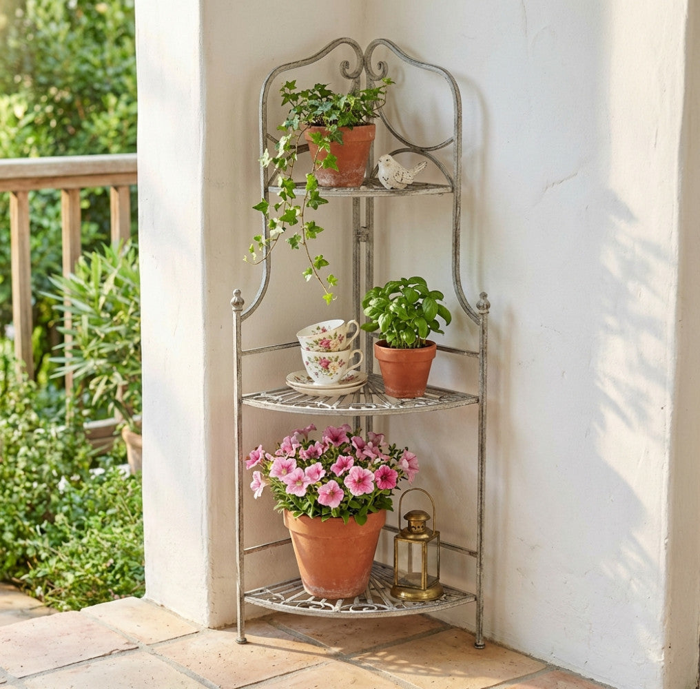 Dettaglio dell'étagère Rosalie a tre piani in un ambiente luminoso, decorata con fiori rosa, piantine e tazze da tè in porcellana.
