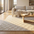 Tappeto Ambroise in lana e cotone bianco beige, steso in un luminoso soggiorno moderno con divano chiaro.