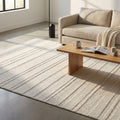 Tappeto moderno Antoine in lana beige ambientato in un salotto luminoso con divano chiaro e tavolino in legno.