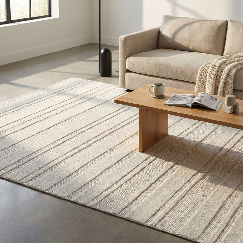 Tappeto moderno Antoine in lana beige ambientato in un salotto luminoso con divano chiaro e tavolino in legno.