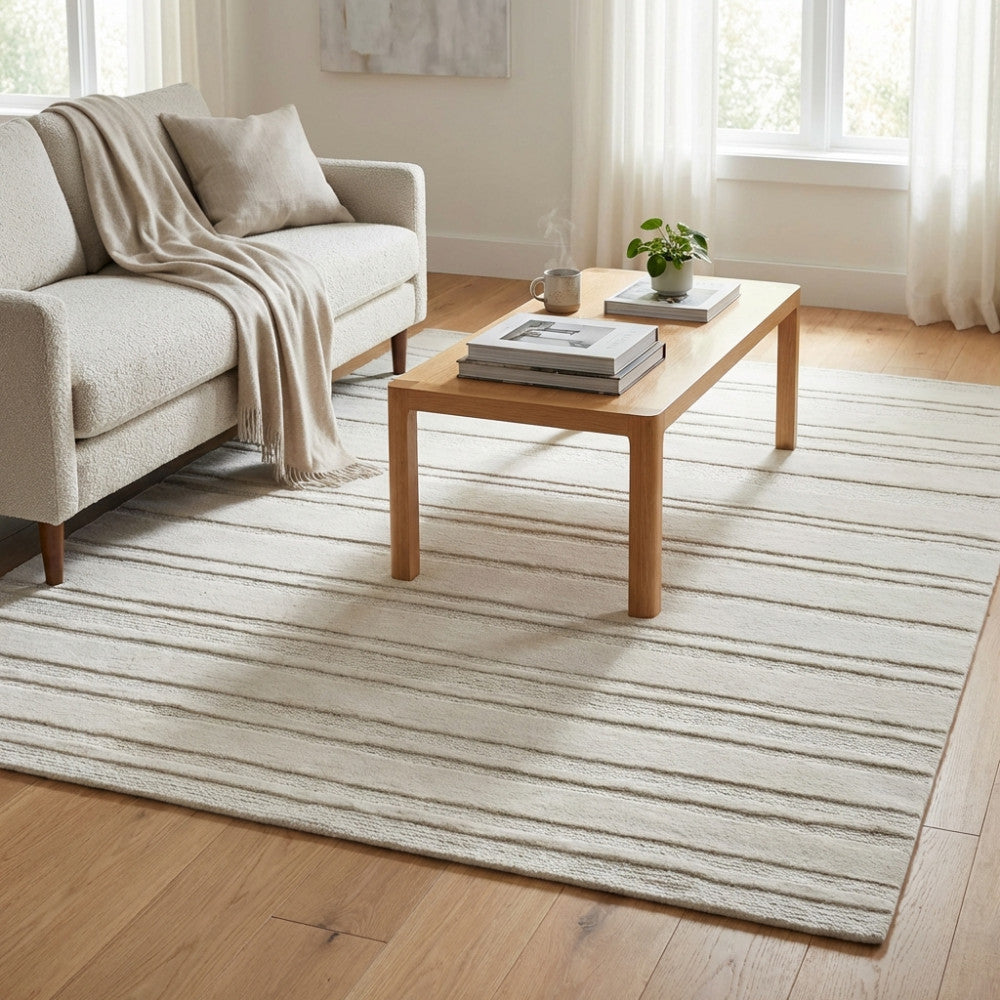 Tappeto Antoine 160x230 in lana e cotone bianco e beige, ambientato in un salotto luminoso con divano chiaro.