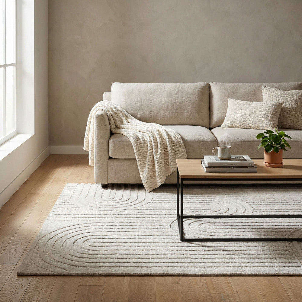 Tappeto Aurélien bianco beige ambientato in un salotto luminoso con divano chiaro e tavolino in legno.