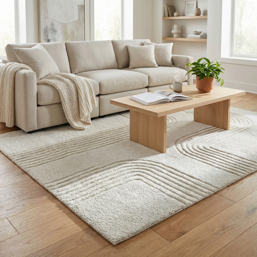 Tappeto moderno in lana bianco beige posizionato in un salotto luminoso con divano chiaro e tavolino in legno.