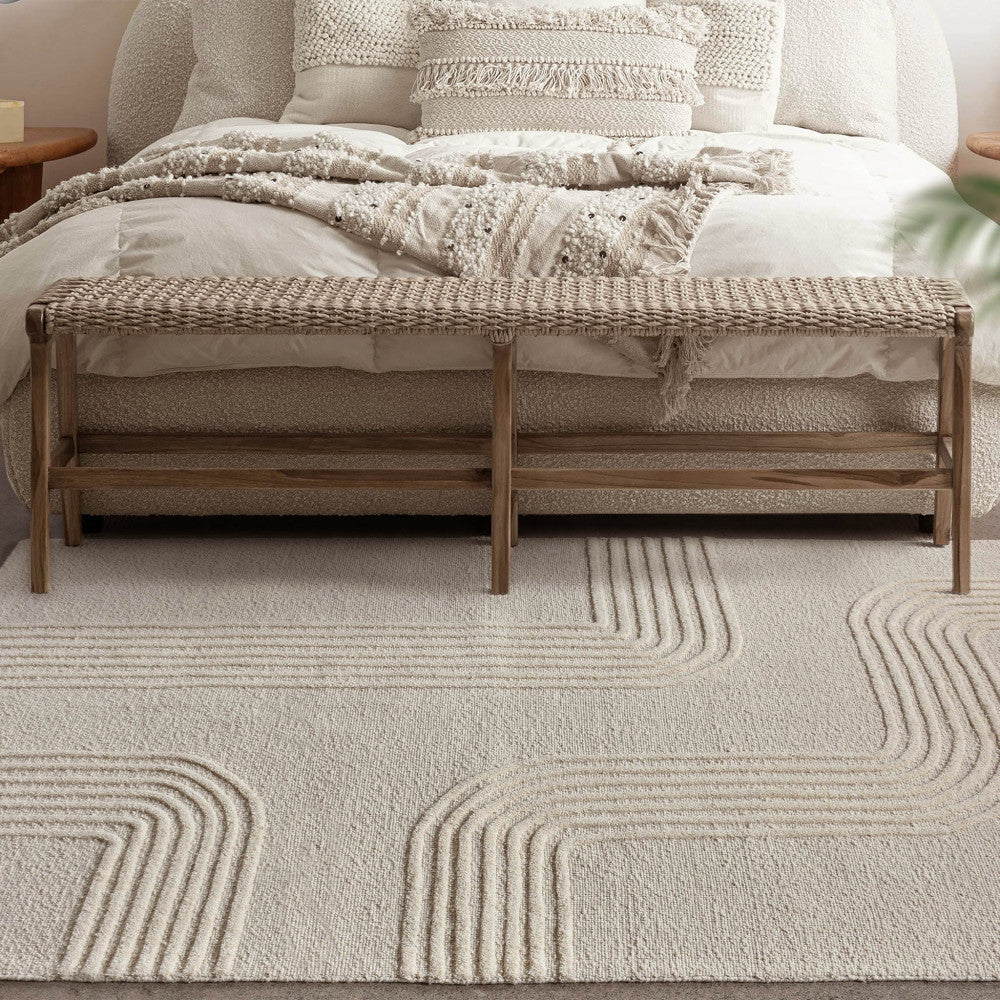 Dettaglio del tappeto bianco beige in una camera da letto elegante con panca rustica e tessuti neutri.